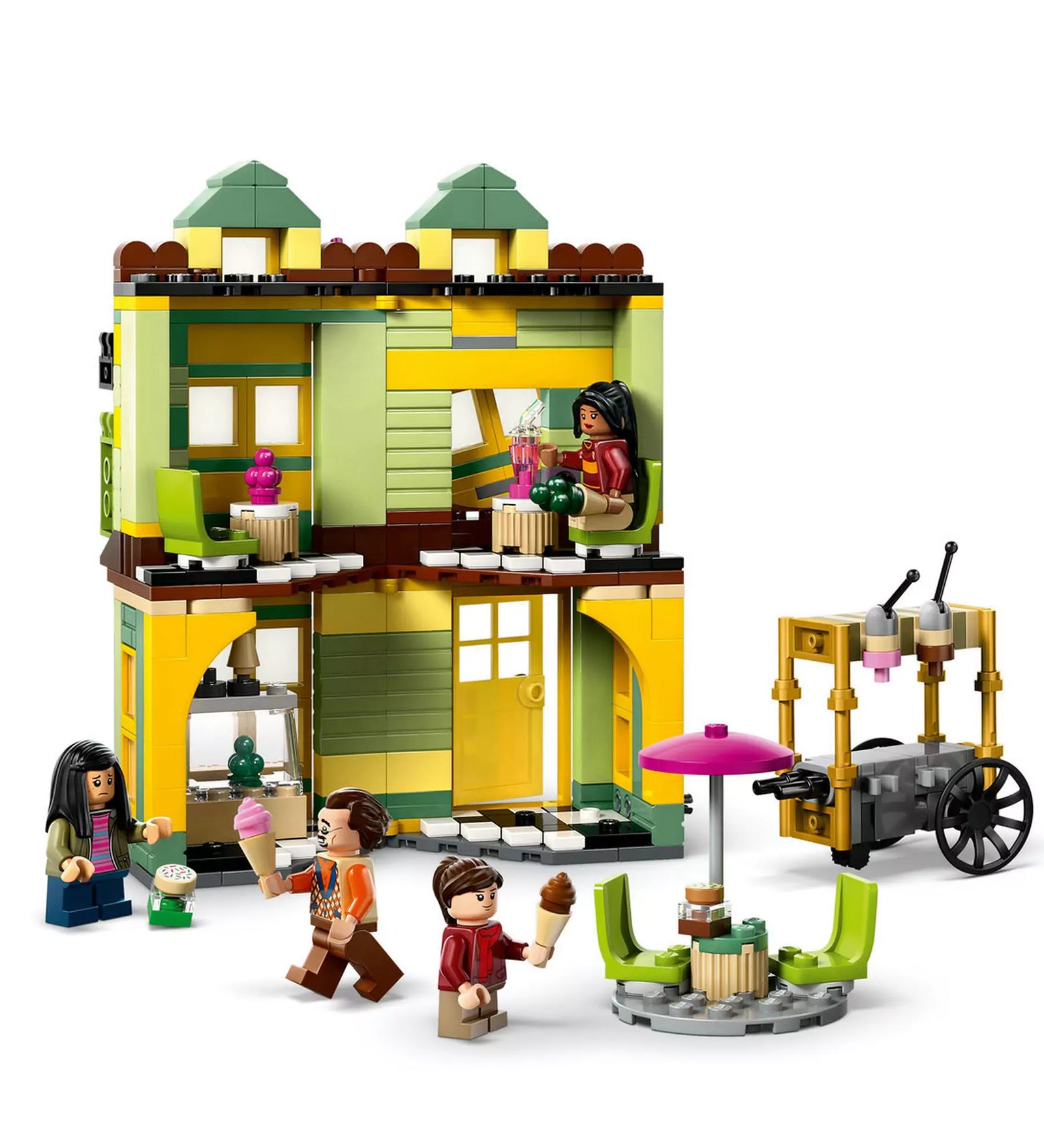 A LEGO Harry Potter 76452 készlet sárga-zöld fagyizójának belső tere, színes bútorokkal, fagylaltos kocsival és három minifigurával.