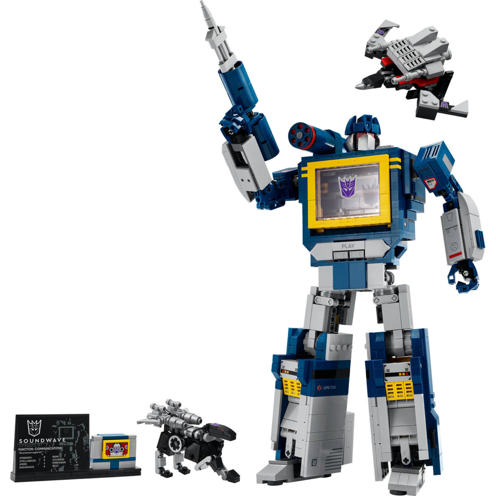 A LEGO Icons Transformers Fülelő (10358) robotfigurája kiegészítőivel – a szürke és kék Soundwave figura fegyverrel pózol, mellette a mini robotok és az információs tábla.