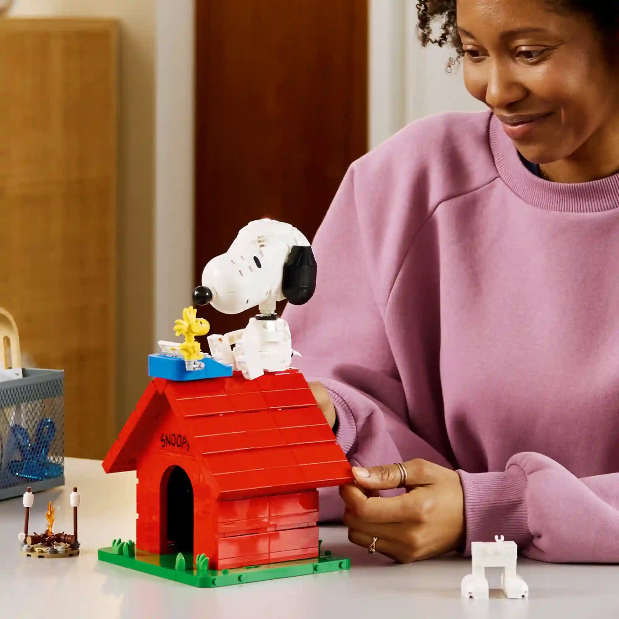 LEGO Ideas Snoopy kutyaháza (21368) életképen, ahol egy rajongó a megépített modellt állítja be, kiemelve Snoopy és Woodstock részletgazdag LEGO figuráit.
