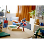 Az Amerika Kapitány LEGO figura kiállítva egy gyerekasztalon, háttérben otthoni környezettel, a figura akciópozícióban, pajzzsal a kezében.