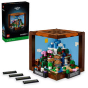 A LEGO Minecraft barkácsasztal készlet doboza és az összerakott díszmodell együtt, cserélhető táblaelemekkel, Minecraft témájú tájképpel és díszes kockafelépítéssel.