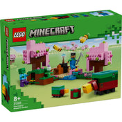 LEGO Minecraft A cseresznyevirágos kert (21260) doboza elölnézetből, a szett világoszöld háttérrel, virágzó rózsaszín fák, méhek, zombik és karakterek jelennek meg rajta.