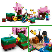 Közelkép a LEGO Minecraft A cseresznyevirágos kert (21260) játékelemeiről: állítható disznó figura, karakter gyémántcsákánnyal, rózsaszín fák és mozgatható részletek.