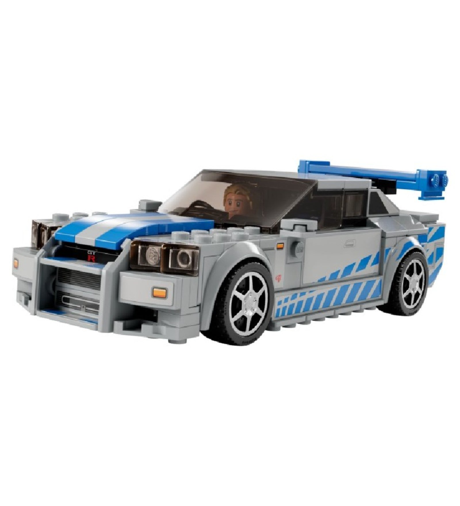 A LEGO Speed Champions Nissan Skyline GT-R (R34) elölnézeti fotója, a volán mögött Brian O’Conner minifigurával, kék-fehér fényezéssel és agresszív hűtőrács kialakítással.