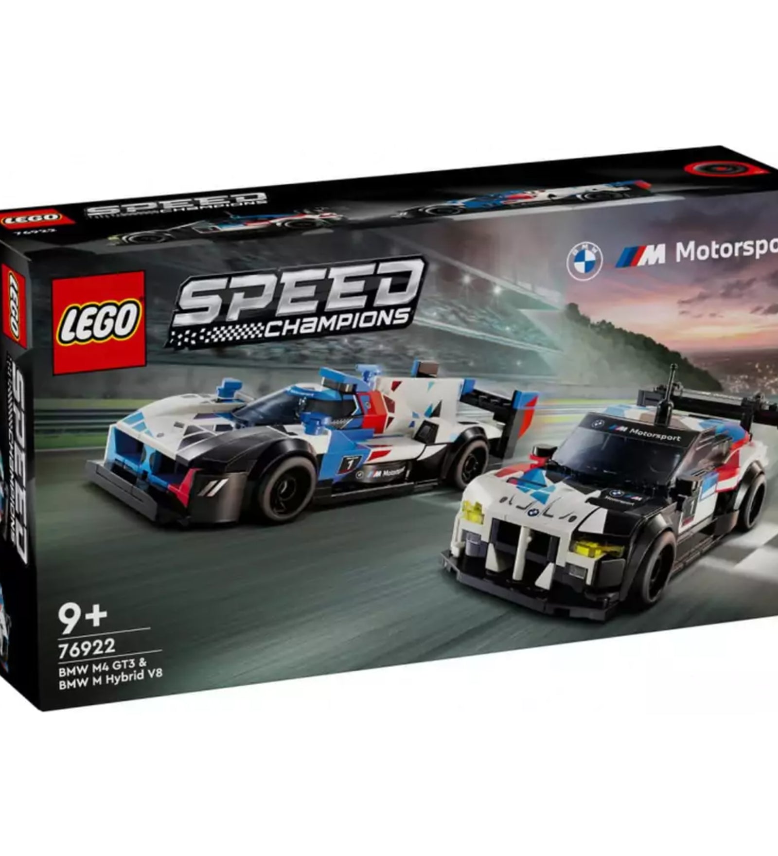 Részletgazdag LEGO Speed Champions 76922 szett doboza, amelyen két BMW versenyautó – a fehér–piros–kék színekben pompázó BMW M Hybrid V8 és a fehér–fekete BMW M4 GT3 – száguld egy versenypályán, a háttérben naplementével.