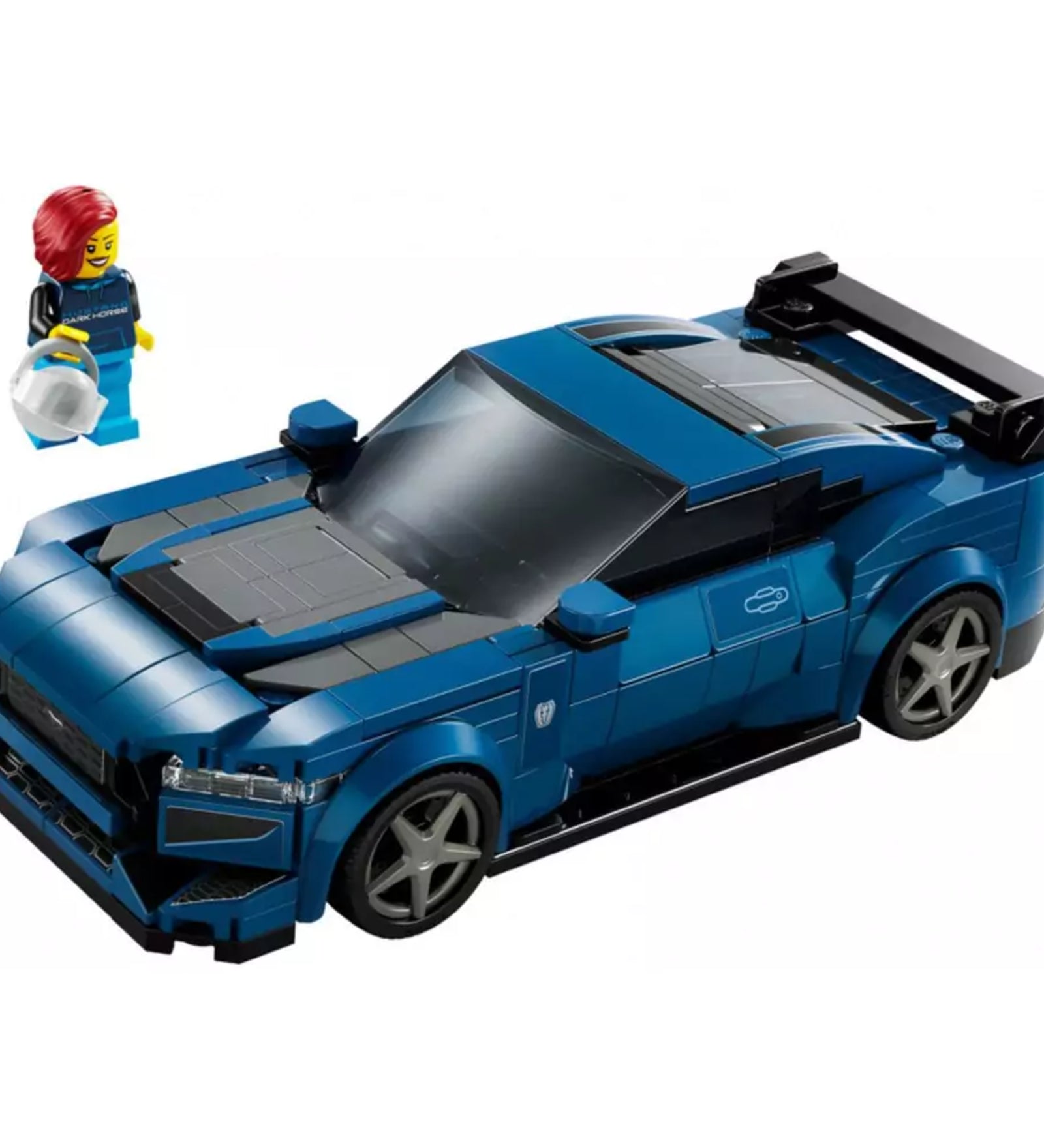 A LEGO Speed Champions Ford Mustang Dark Horse (76920) teljes készlete, sötétkék LEGO autómodell nagy hátsó szárnnyal, mellette a piros hajú pilóta minifigura világoskék overallban és fehér sisakkal.