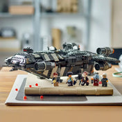 A LEGO Star Wars Onyx Cinder (75374) készlet kiállítva egy asztalon, az űrhajó mögött sorakoznak a minifigurák egy lakásbelső környezetében.