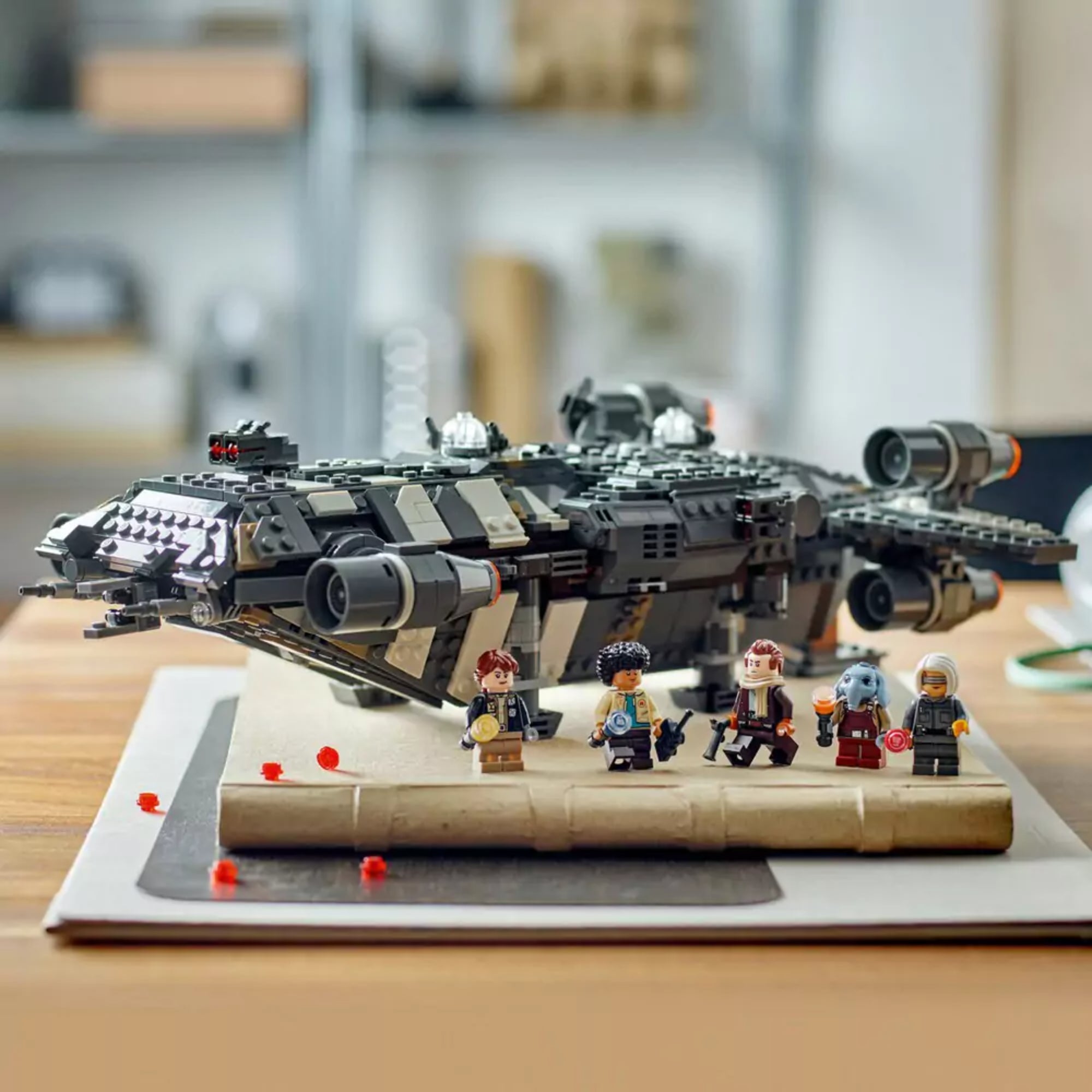 A LEGO Star Wars Onyx Cinder (75374) készlet kiállítva egy asztalon, az űrhajó mögött sorakoznak a minifigurák egy lakásbelső környezetében.