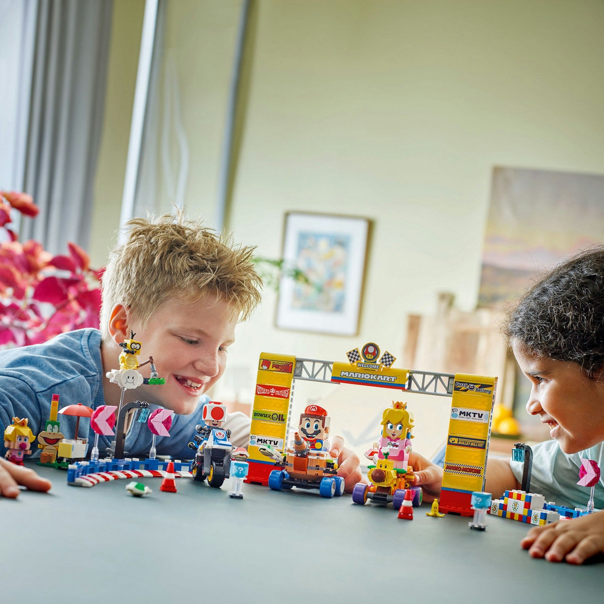 Két gyerek éppen a LEGO Super Mario Mario Kart Baby Peach és Grand Prix szett (72036) versenypályáján játszik boldogan.