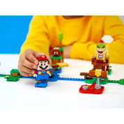 Egy gyerek épp irányítja a LEGO Super Mario figurát az összeszerelt pályán, ahol ellenségek és akadályok várják a Mario kalandjai kezdőpálya (71360) szettből.