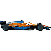 A LEGO Technic McLaren Formula 1 versenyautó (42141) teljes oldalnézete – A jármű profilból fotózva, jól látható a teljes hossz, a fekete szárnyak, a kék peremes gumik és az alacsony felfüggesztés.