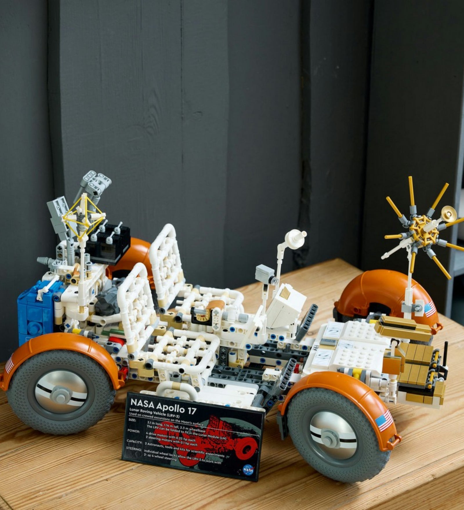 „LEGO Technic NASA Apollo holdjáró jármű (42182) összerakott modellje fa felületen, jól látható részletekkel: antenna, ülések és információs tábla a jármű előtt.”