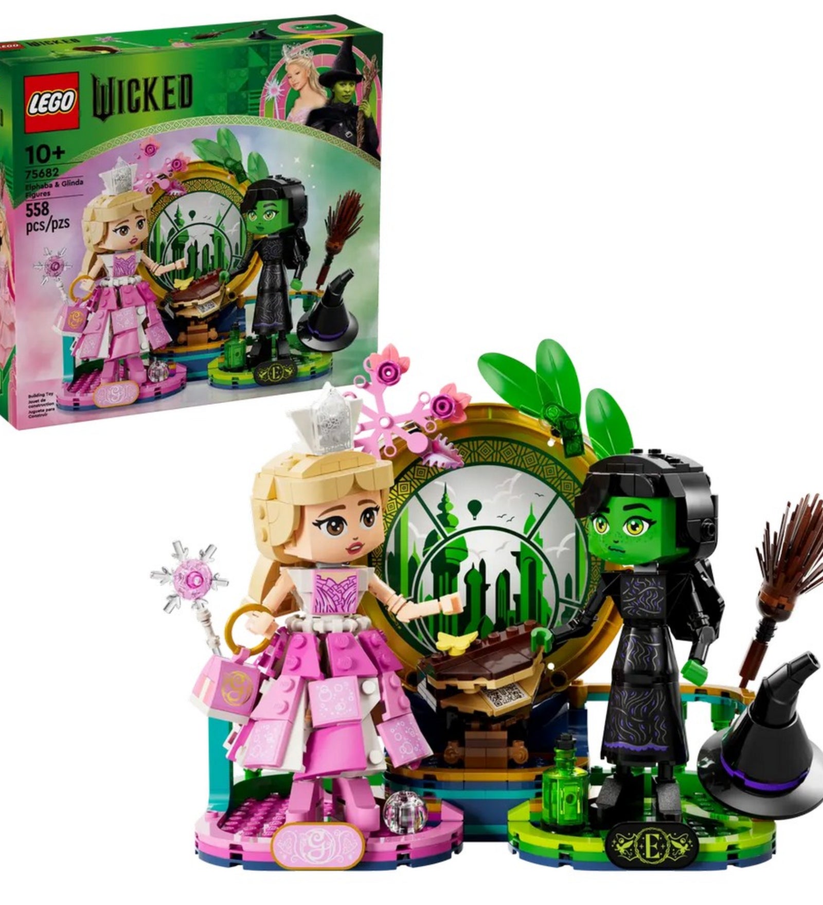 A készlet és a doboz együtt, teljes pompájában: Glinda rózsaszín ruhában, Elphaba fekete öltözetben, varázslatos smaragd háttérrel.