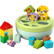 LEGO DUPLO Formaválogató házikó (10441) játék közben, különböző formájú kockák a megfelelő nyílások fölé helyezve, kutyusos grafikákkal díszítve.
