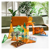 MAGNA-TILES Safari Animals mágneses építőkészletből készült szafari jelenet egy asztalon, elefánttal, zsiráffal, oroszlánnal és majommal.