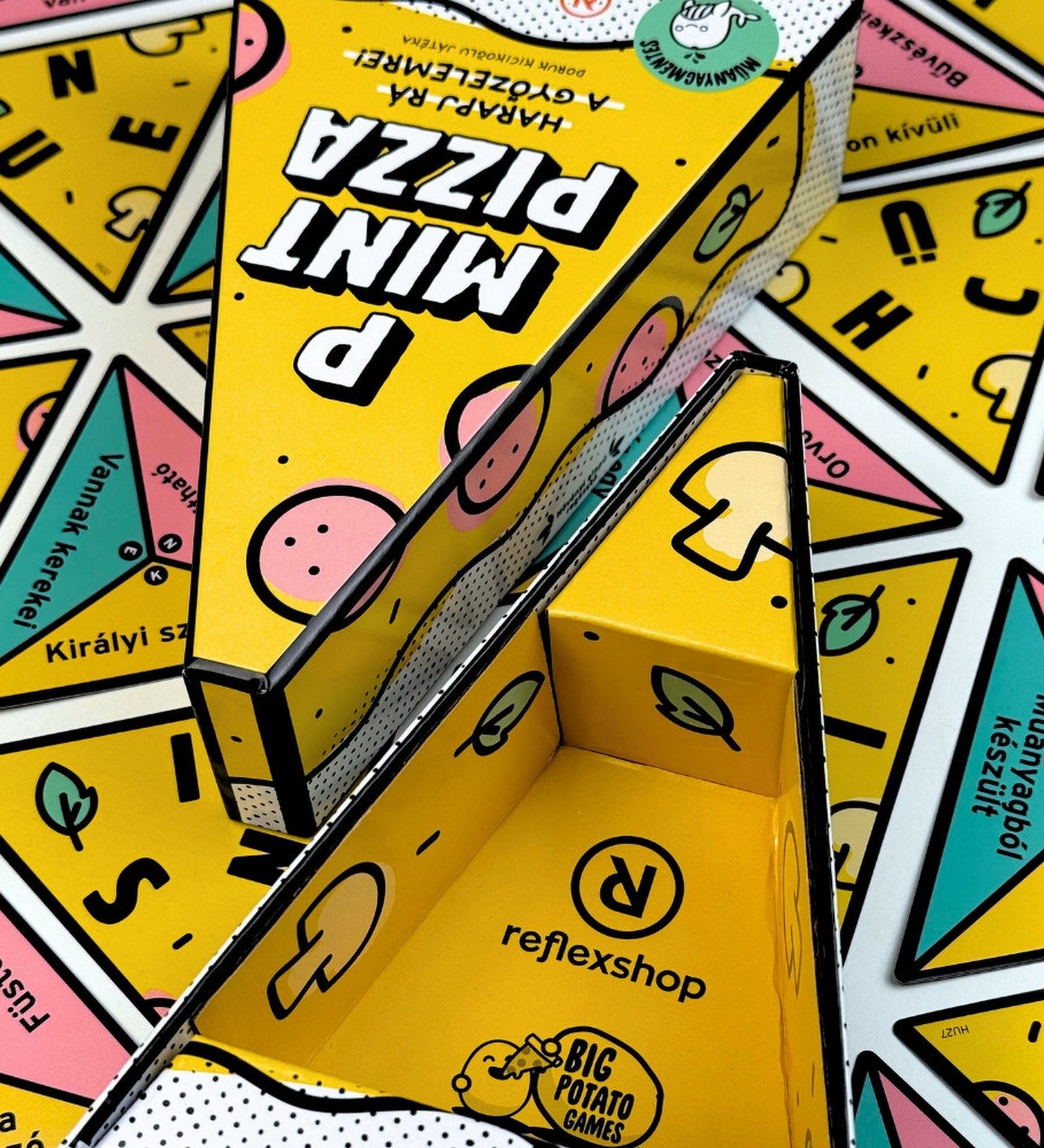 P Mint Pizza társasjáték dobozának belső kialakítása felnyitva, pizza szelet formájú tárolóval, sárga színű belső grafikával, Reflexshop és Big Potato Games logóval.