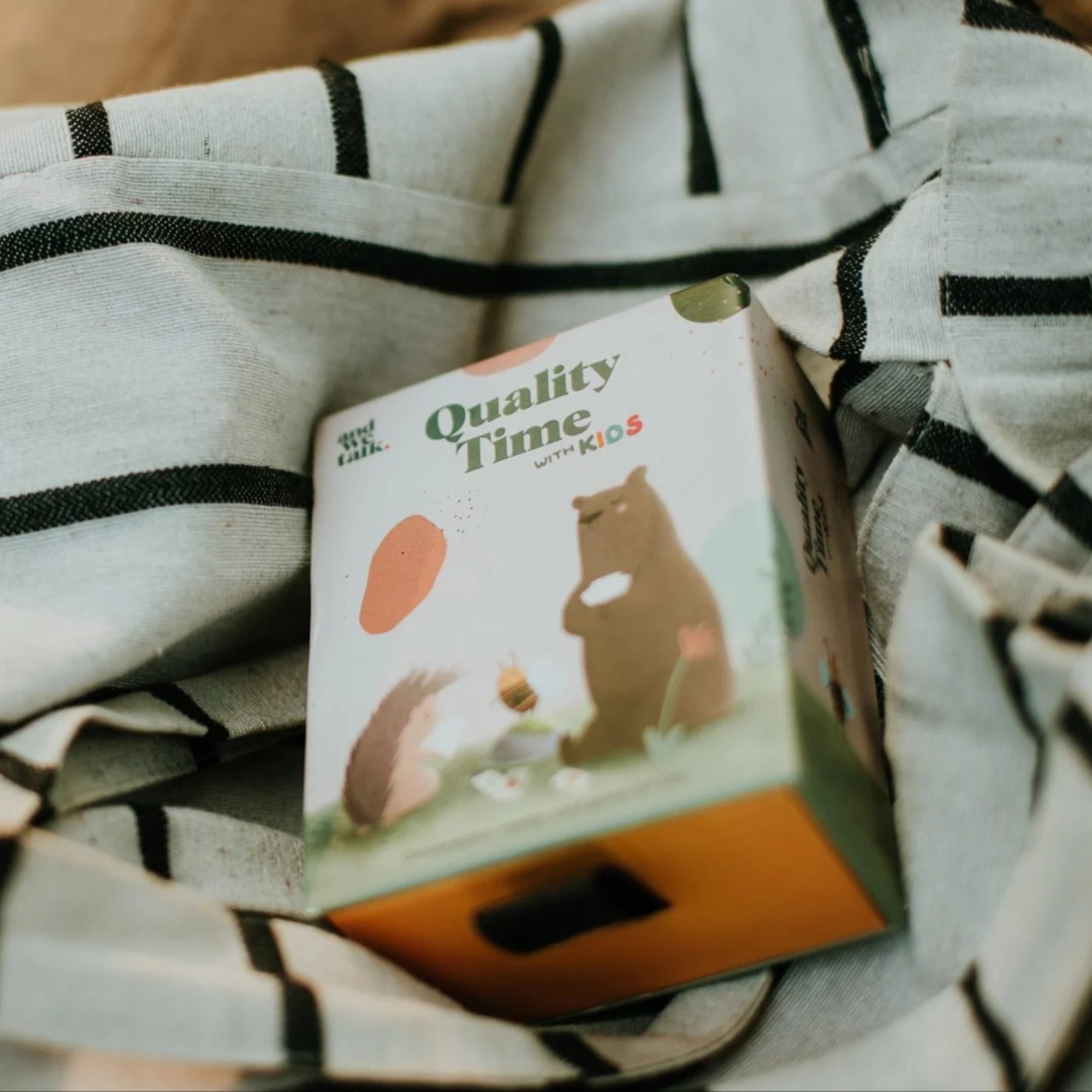 Quality Time with Kids beszélgetésindító kártyajáték doboza, textil felületen, hangulatos fotón