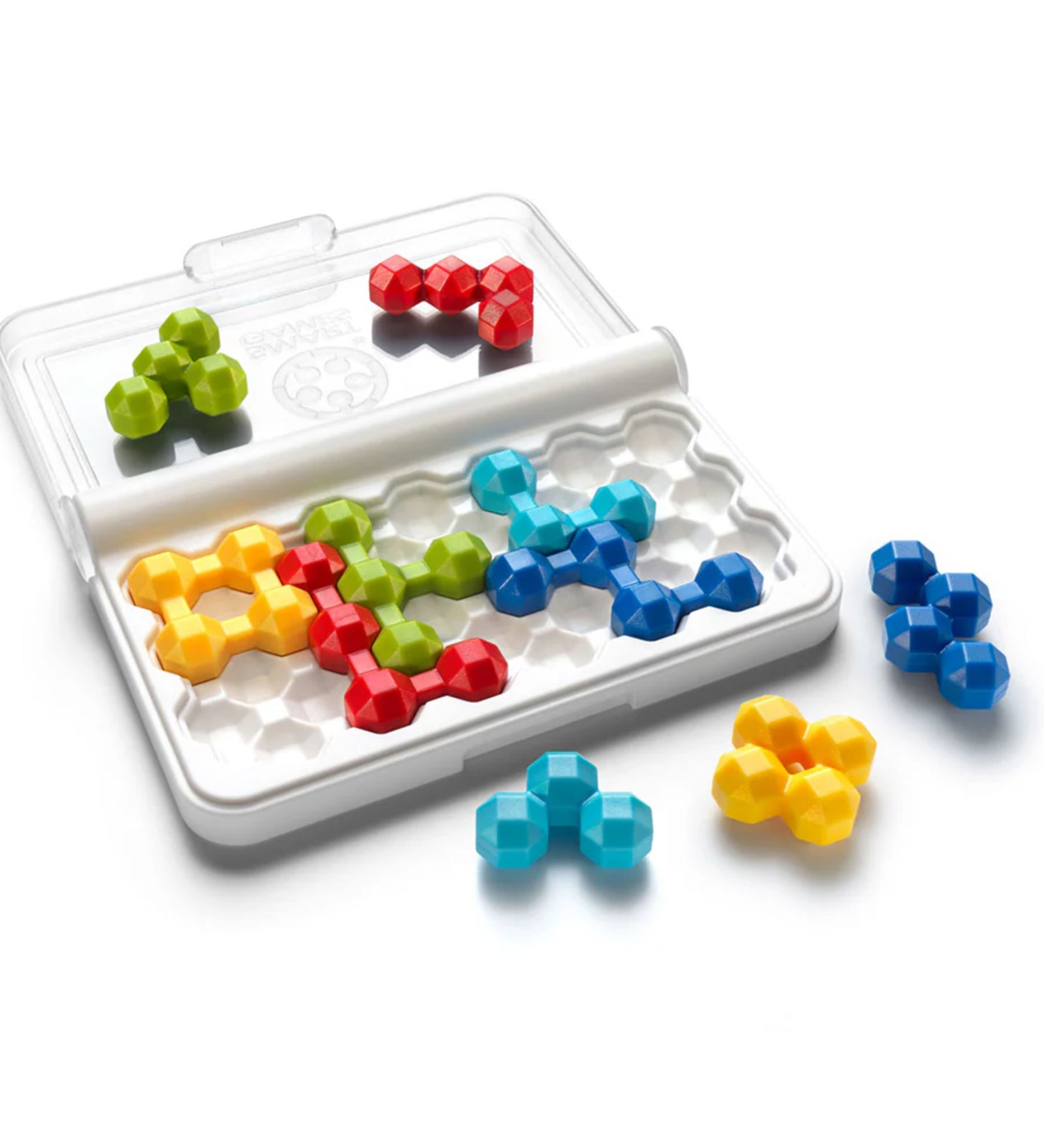 A képen a Smart Games IQ Twins logikai játék belső tartalma látható közelebbről. A fehér, zárható tok nyitott állapotban van, és jól látszanak benne a hatszög alakú mélyedések, amelyekbe a különböző színű, háromdimenziós puzzle-elemek illeszkednek. A játék darabjai élénk színűek (piros, zöld, sárga, kék, világoskék), és mindegyik forma egyedi kialakítású, mégis párban szerepelnek – de nem teljesen egyformák! 