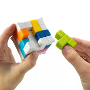 Kézben tartott Plug & Play Puzzler kocka, játékos éppen egy zöld puzzle elemet illeszt a színes 3D kockába.