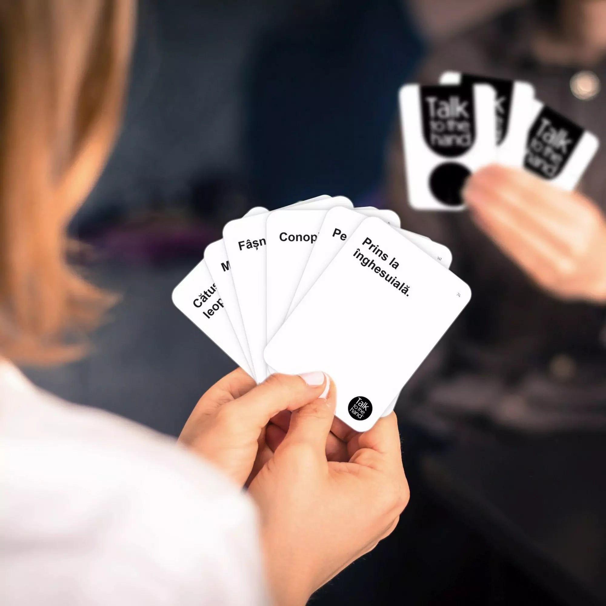Talk to the Hand, felnőtteknek szóló partijáték – közelkép egy játékos kezéről, aki öt vicces, román nyelvű fehér kártyát tart.