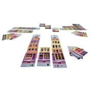  Játék közbeni elrendezés a Táncoló Házak társasjátékból, egymásra épített, színes házkártyákkal és húzópaklikkal.