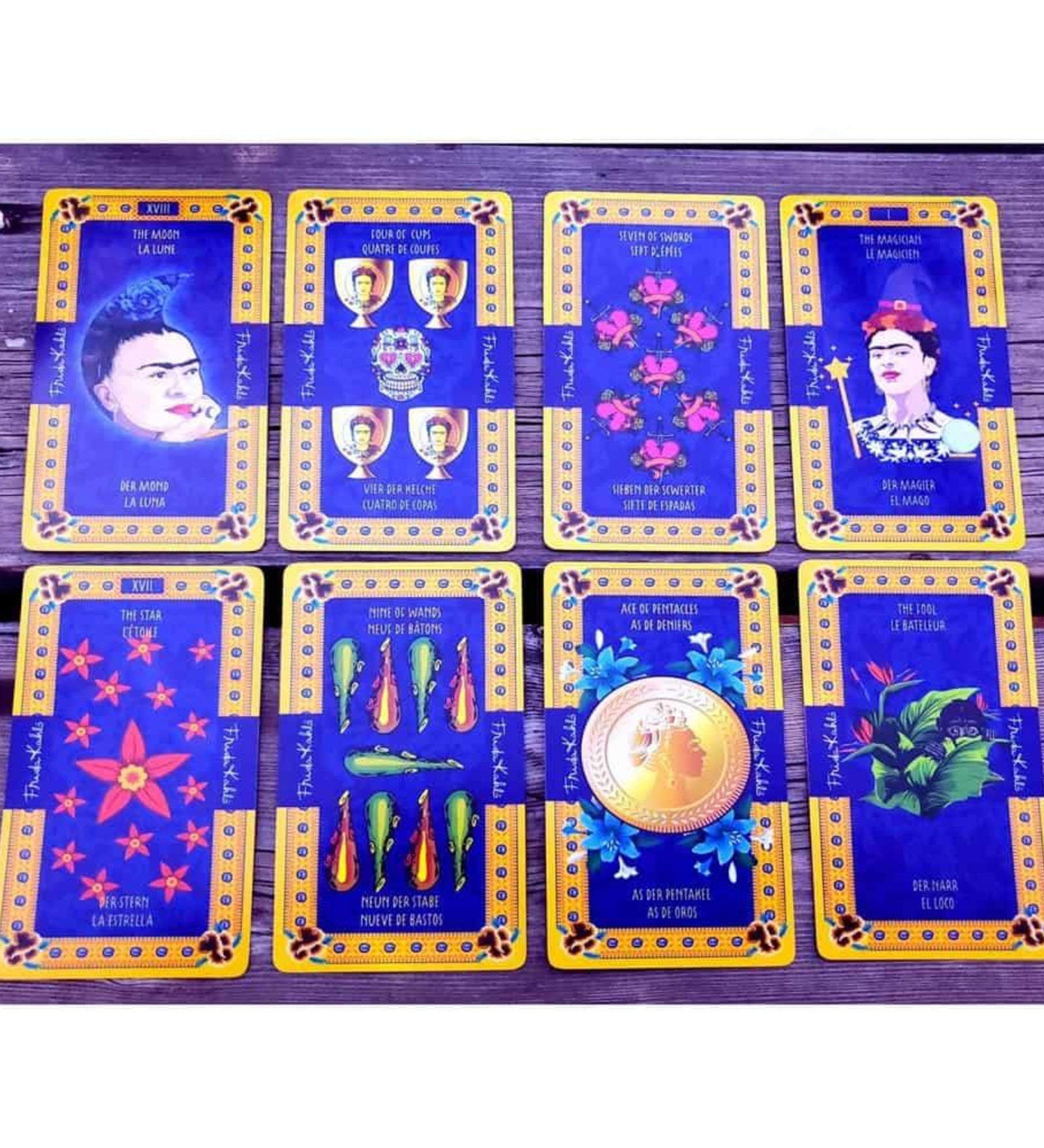 A képen a Frida Kahlo Tarot kártyacsomag egy válogatott lapjai láthatók, színes és gazdagon díszített dizájnnal. A kártyák domináns színe a mélykék és arany, amelyet virágminták és mexikói népművészeti motívumok egészítenek ki. Több kártyán is megjelenik Frida Kahlo portréja, különböző szimbólumokkal kiegészítve. A „The Magician” és „The Moon” lapokon a festőnő ikonikus arcképe szerepel, míg más lapokon paprikák, virágok, aranyérmék és festmények utalnak Frida életére és művészetére. 