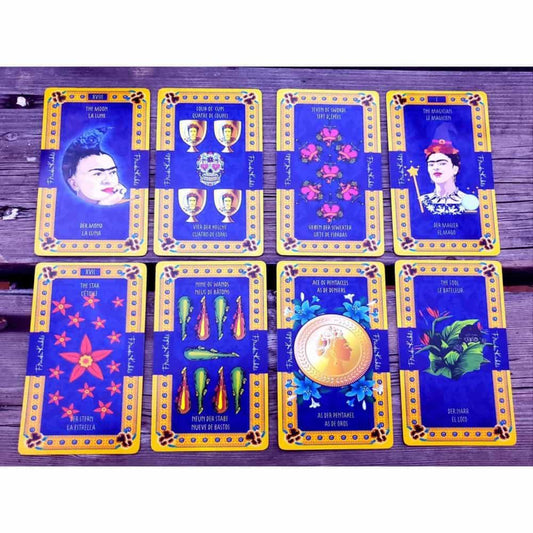 A képen a Frida Kahlo Tarot kártyacsomag egy válogatott lapjai láthatók, színes és gazdagon díszített dizájnnal. A kártyák domináns színe a mélykék és arany, amelyet virágminták és mexikói népművészeti motívumok egészítenek ki. Több kártyán is megjelenik Frida Kahlo portréja, különböző szimbólumokkal kiegészítve. A „The Magician” és „The Moon” lapokon a festőnő ikonikus arcképe szerepel, míg más lapokon paprikák, virágok, aranyérmék és festmények utalnak Frida életére és művészetére. 