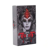 A képen a XIII Tarot by Nekro kártyapakli doboza látható. A doboz dizájnja sötét, misztikus és rendkívül részletgazdag: egy fekete-fehér tónusú, gótikus stílusú női arc dominálja a borítót, amelyet vörös díszítés emel ki a homlok közepén. A háttér gazdagon díszített, szinte már fémes hatású mintákkal. A dobozon a "XIII Tarot" felirat olvasható erőteljes, vörös betűtípussal, alatta "by Nekro" jelzéssel.
