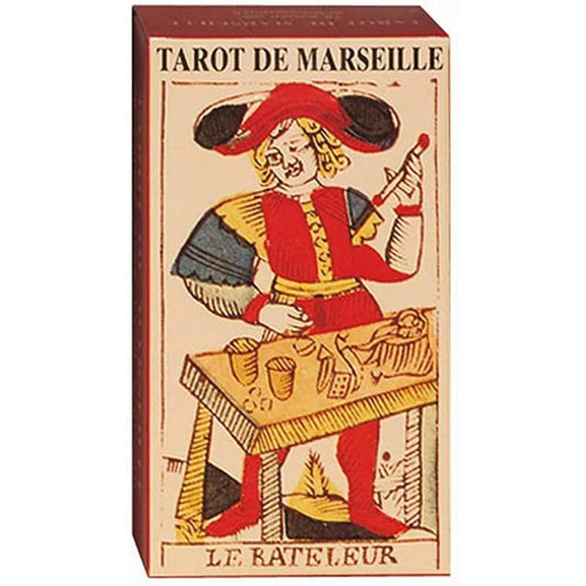 A képen a klasszikus Tarot de Marseille kártyacsomag doboza látható. A doboz előlapján a híres Le Bateleur (A bűvész) lap illusztrációja szerepel, amely élénk vörös, sárga és fekete színekkel van megrajzolva, a 18. századi stílusnak megfelelően. A bűvész egy asztal mellett áll, ahol különféle tárgyak – poharak, dobókockák, érmék – utalnak a manipuláció és lehetőségek szimbólumára. A klasszikus francia tarot egyik legismertebb alakját láthatjuk, amely hűen tükrözi a pakli történelmi és szimbolikus értékét.