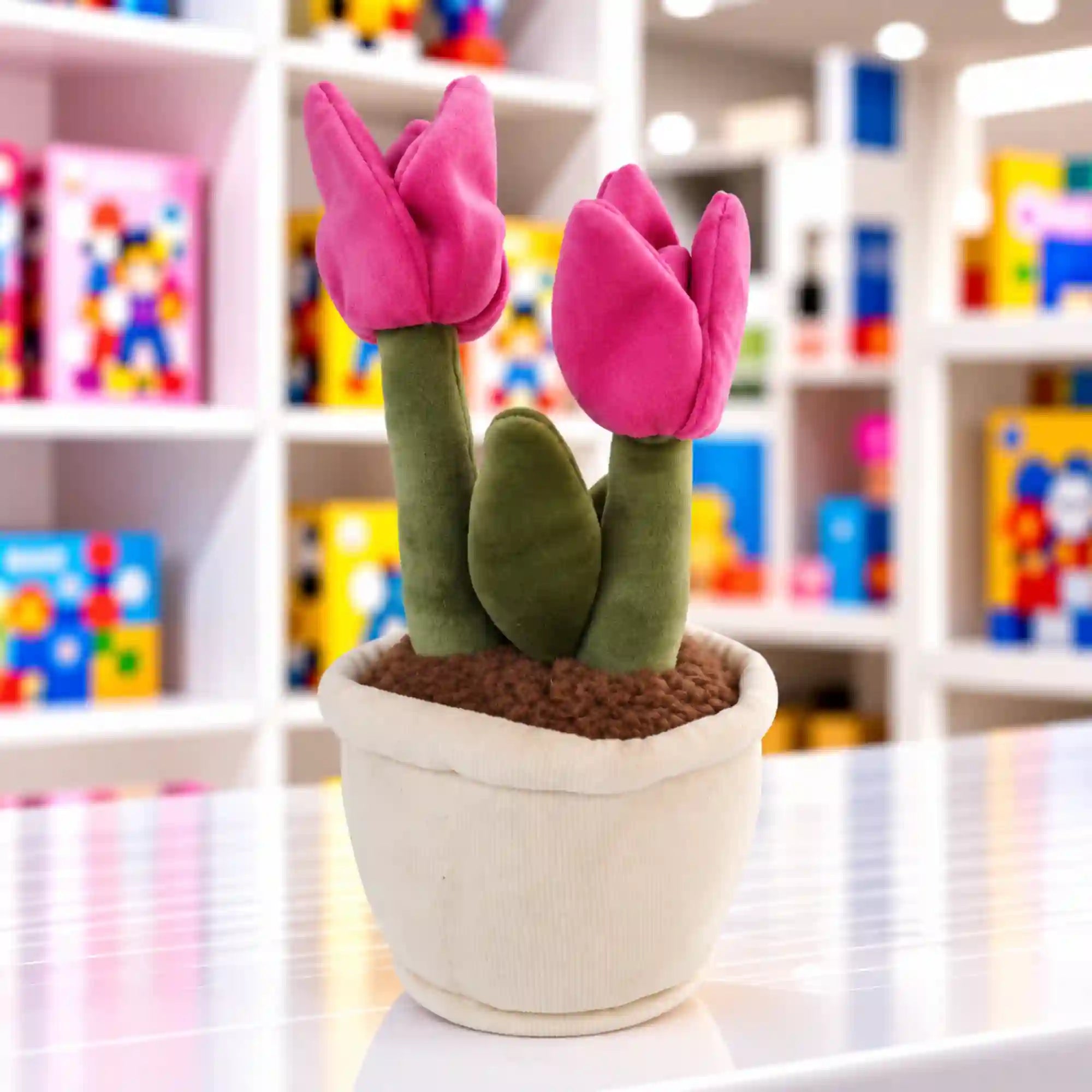 Tulipános virágcserép plüssfigura két élénk rózsaszín tulipánnal, zöld szárakkal és levéllel, barna plüssfölddel és puha, fehér kaspóval.