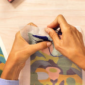 Atelier 65 hímzőkészlet – kézben tartott vászon, amelyre a felhasználó kék fonallal hímez.