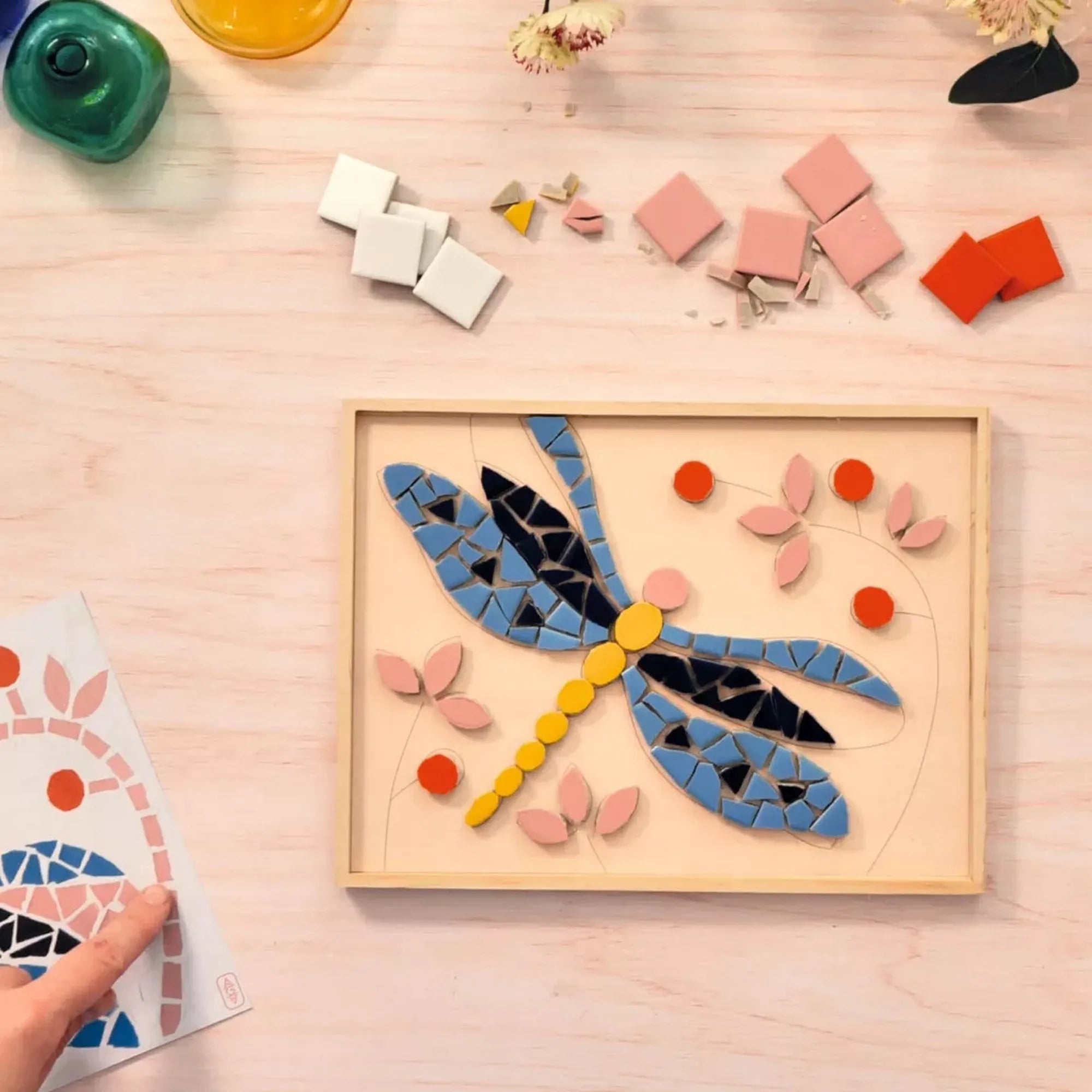 Atelier 72 mozaikkészítő felnőtteknek: Szitakötő – színes mozaiklapokból kirakott szitakötő mintakép fa keretben, felülnézetből.