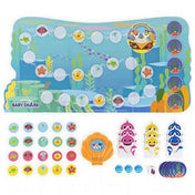 A Baby Shark: Party at the Reef játéktábla és elemei kiterítve: színes korallzátony mintás pálya, arany kagyló alakú zenei egység, különböző állatos zsetonok, dobókocka és cápafigurák.