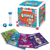 A BrainBox: Știință játék tartalma kibontva: a doboz mellett egy homokóra, egy kék dobókocka és több színes kártya, rajtuk tudományos témák, mint gravitáció, emésztőrendszer és madarak.