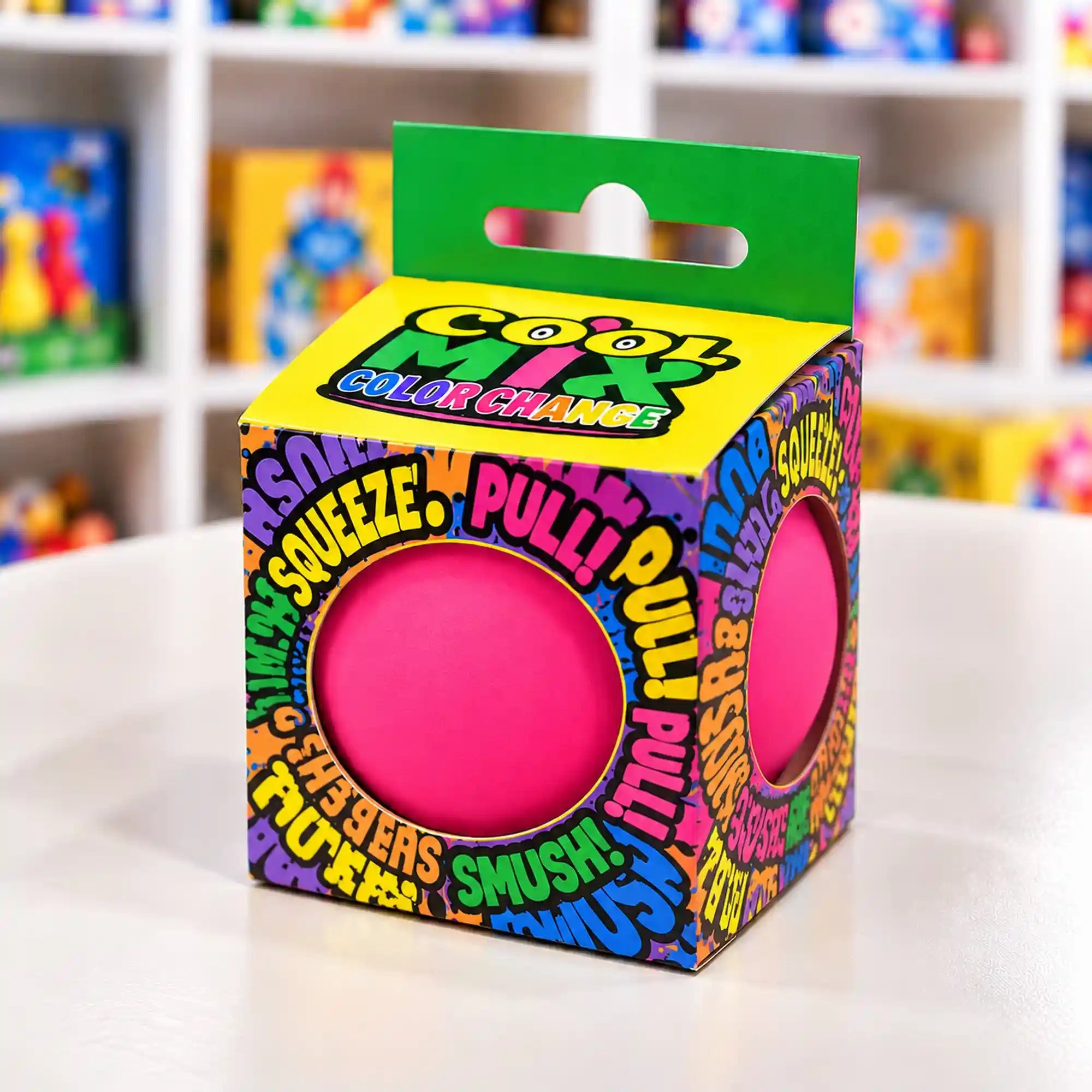 Cool Mix Squishy 7 cm stresszlevezető játék (rózsaszín) – Élénk rózsaszín squishy labda színes, feliratos dobozban, játékbolti polcok előtt.