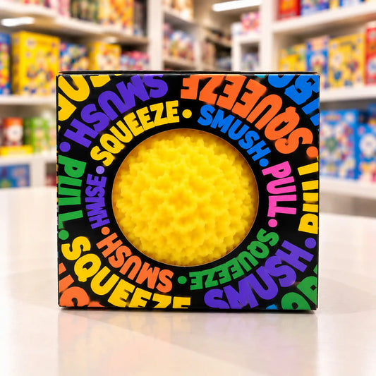 Cool Mix Squishy: Bolyhos tapintású labda 6 cm stresszlevezető játék (sárga), fekete, színes feliratokkal díszített dobozban, kerek ablakon keresztül látható.