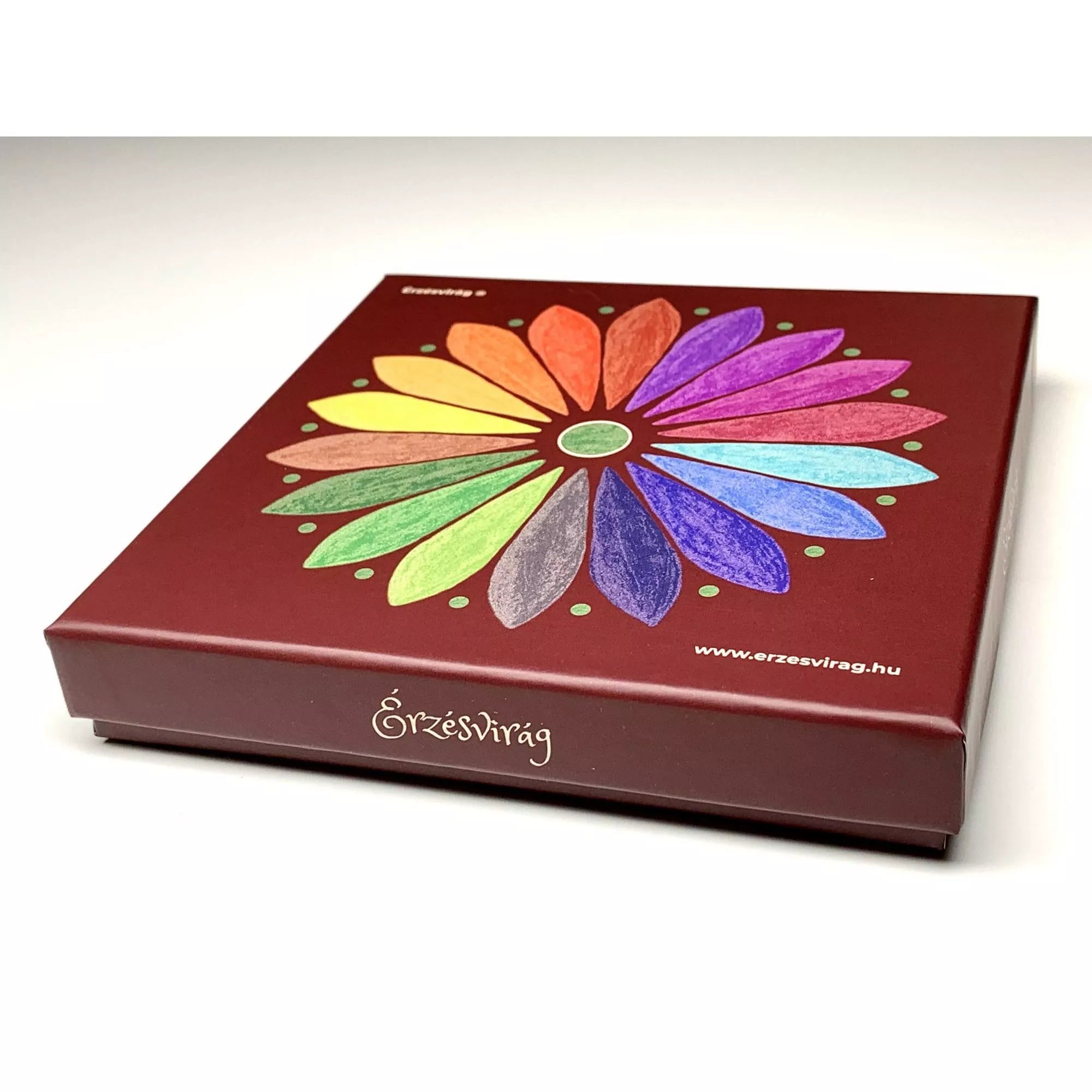 A bordó színű Érzésvirág doboz teteje, közepén a színes, 20 sziromból álló érzelemvirággal. A sziromszínek a különböző érzelmi kategóriákat jelölik, a design letisztult és esztétikus. A dobozon az Érzésvirág logó és a gyártó webcíme is látható.