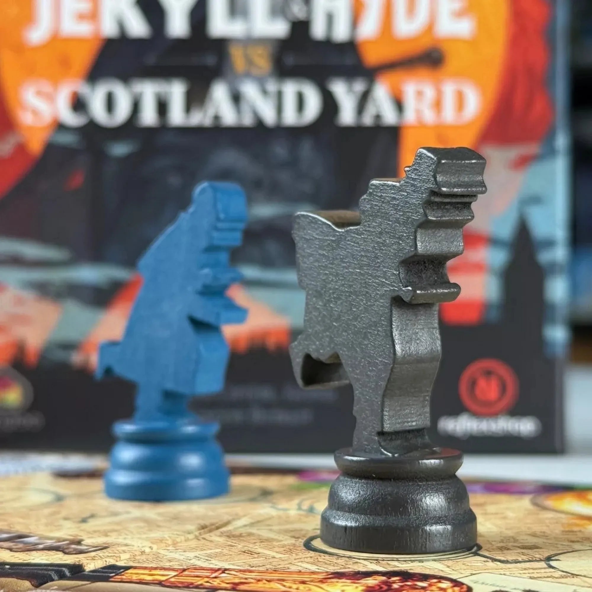 A Jekyll & Hyde vs Scotland Yard két ikonikus figurája – Dr. Jekyll és Mr. Hyde – fa bábuk formájában, a játéktáblán elhelyezve.