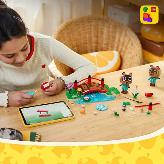 A LEGO Animal Crossing: Timmy és Tommy vidám kirándulása 77059 készlettel egy gyermek építi a piros hidat és a tóparti jelenetet a LEGO Builder alkalmazás útmutatóját követve, miközben Timmy és Tommy figurái, valamint a kiegészítők az asztalon sorakoznak.