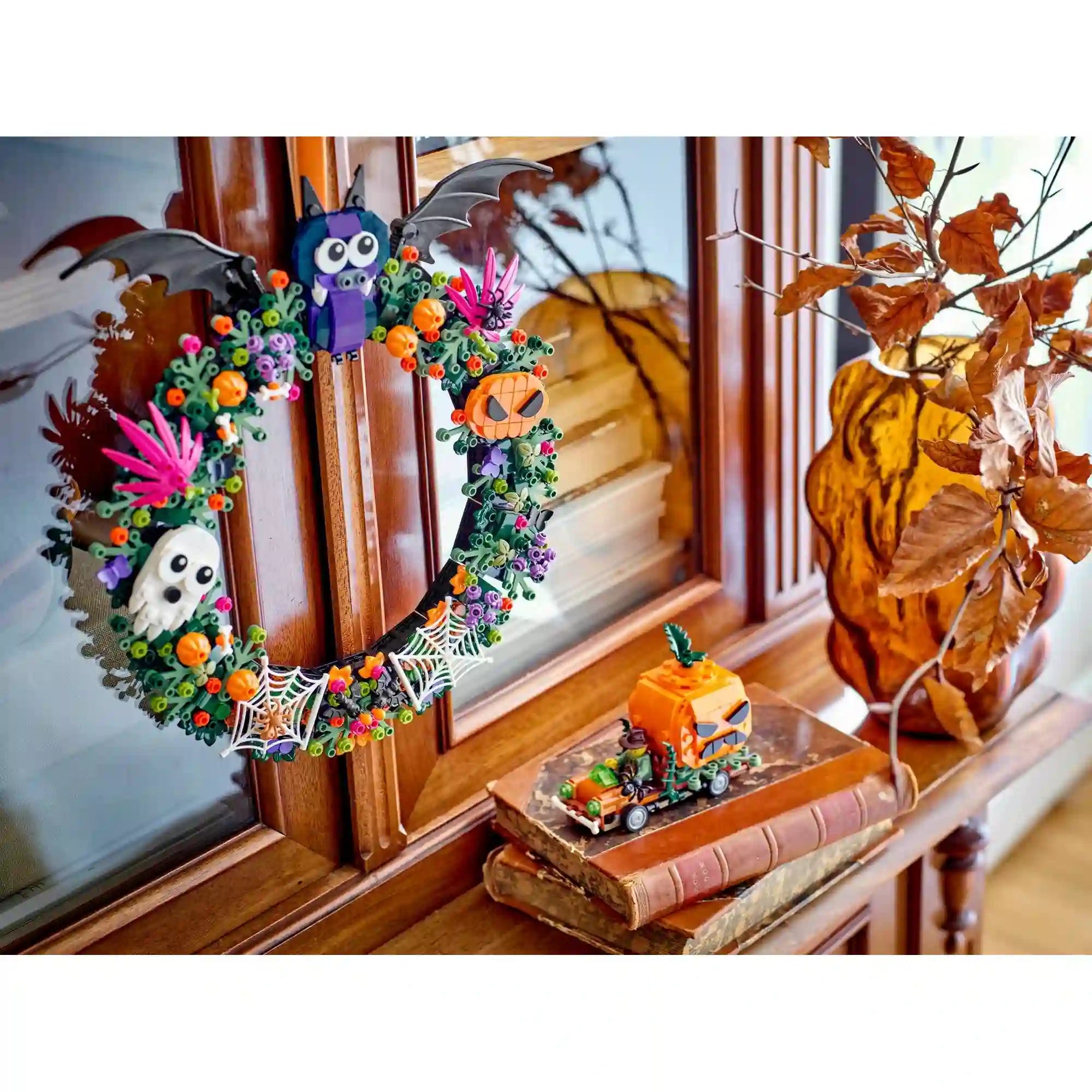 LEGO Halloweeni koszorú 40825 fa szekrényre akasztva, denevérrel, szellemmel, tökökkel és mellette egy kis LEGO járművel.