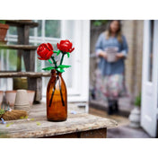LEGO Roses (40460) piros rózsák rusztikus faasztalon barna üvegben, háttérben kerthelyiséggel és elmosott alakkal