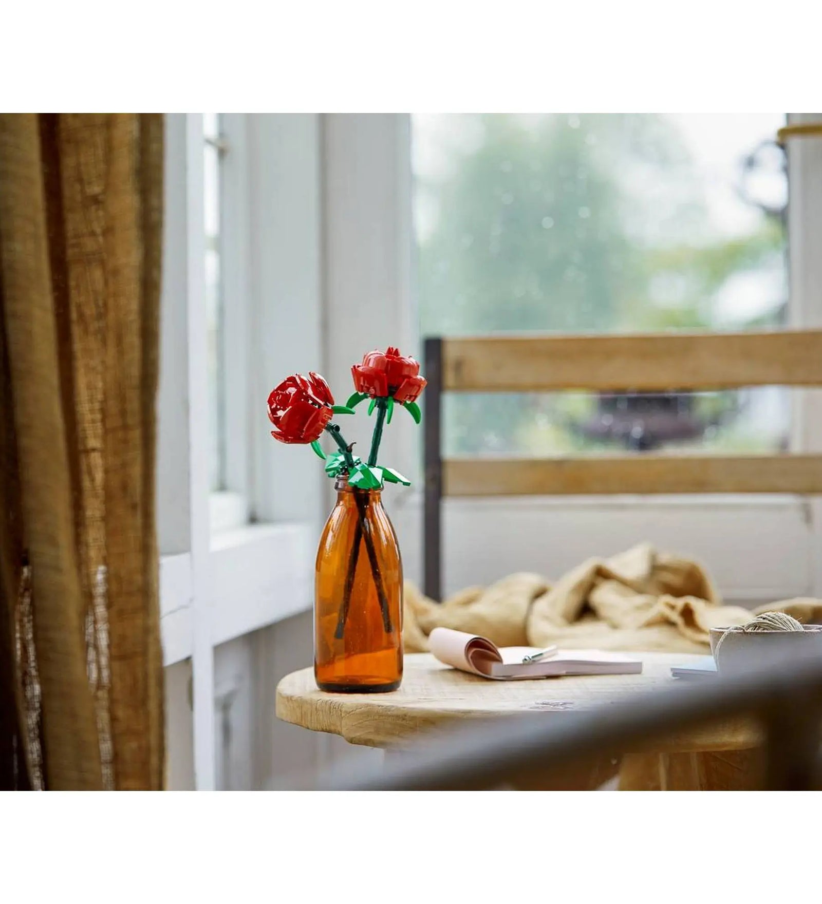 LEGO Botanicals Roses (40460) megépített vörös rózsák barna üvegpalack vázában, világos nappali enteriőrben elhelyezve