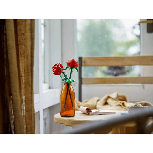 LEGO Botanicals Roses (40460) megépített vörös rózsák barna üvegpalack vázában, világos nappali enteriőrben elhelyezve