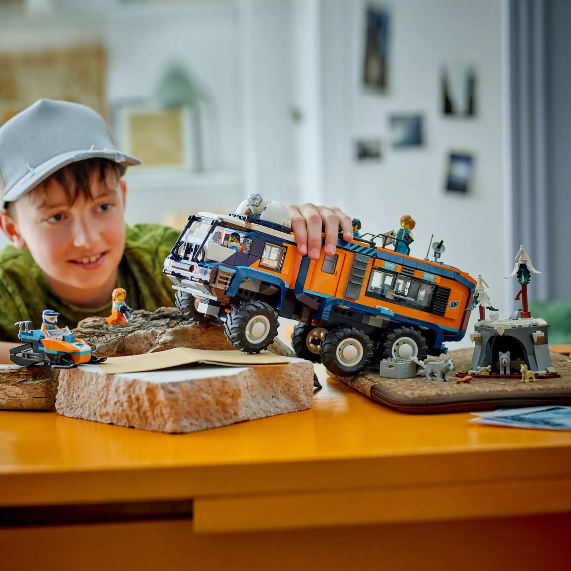 Gyerek játszik a LEGO City Arctic Truck (60471) készlettel, élethű havas díszlettel és farkasos barlanggal a háttérben.