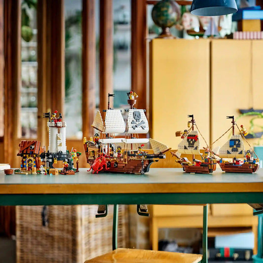 A LEGO Creator Ikonikus kalózhajó (31387) készlet mindhárom építési lehetősége egy asztalon. A jeleneten a kalózhajó, a kalózkastély és a két kisebb ikerhajó látható kalóz minifigurákkal és kiegészítőkkel.