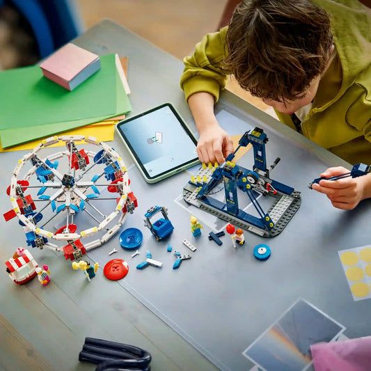 Gyermek építi a LEGO Creator 3 az 1-ben Ikonikus óriáskerék (31389) készletet. Az asztalon részben összeépített óriáskerék, szétszórt LEGO elemek, minifigurák és a LEGO Builder alkalmazást futtató táblagép látható.