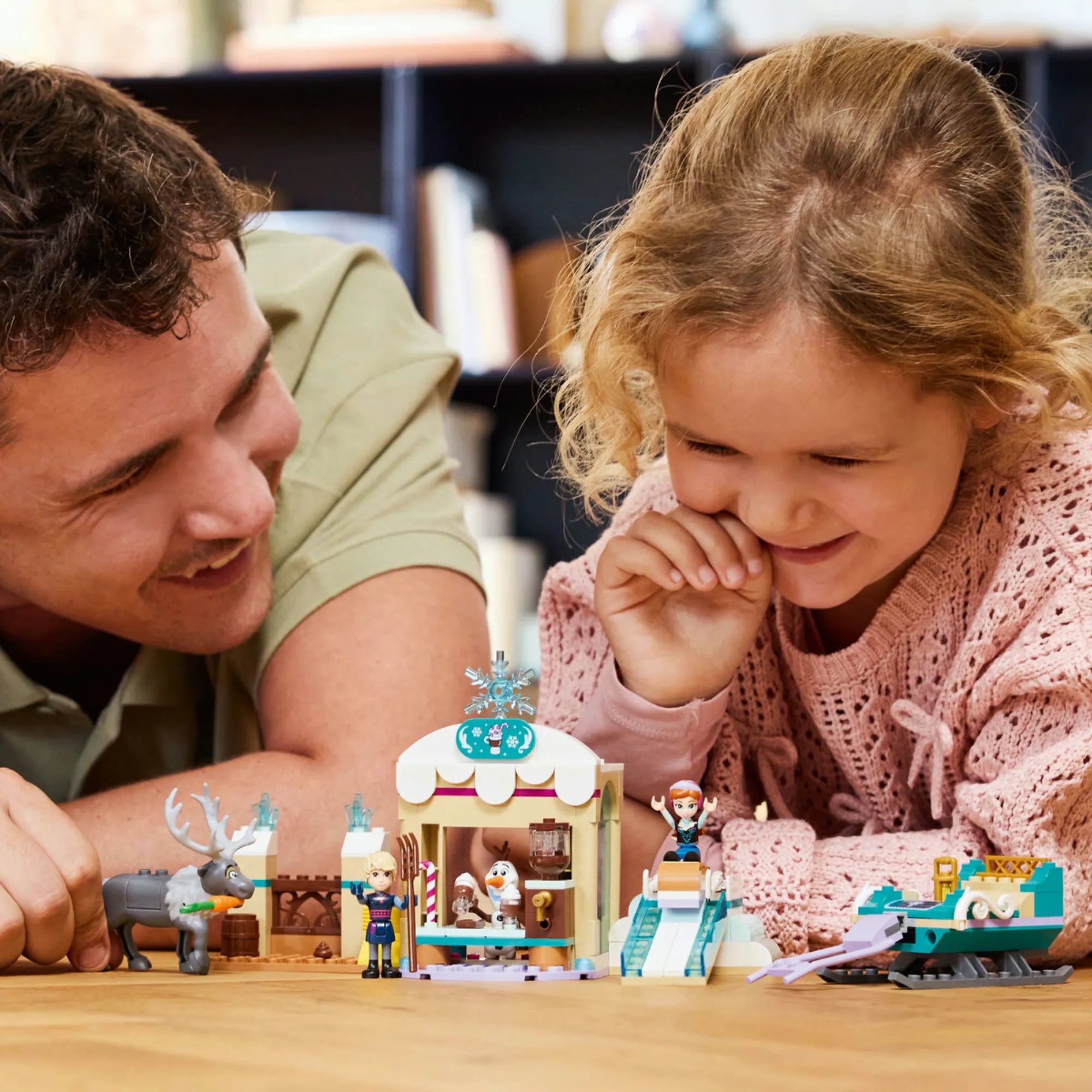 Egy gyermek és szülő játszik a LEGO Disney Anna szánkózós kalandjai (43256) szettel, megosztva a téli élményeket.