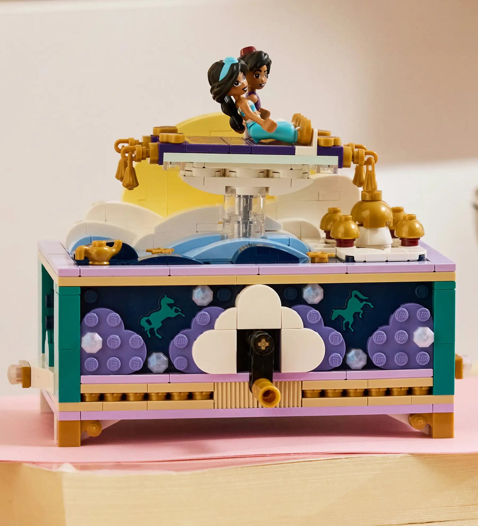 LEGO Disney: Jázmin ékszerdoboza 43295, 458 darabos készlet megépített ékszerdoboza, amelynek tetején Jázmin és Aladdin a repülő szőnyegen ülnek a felhők és a hold előtt.