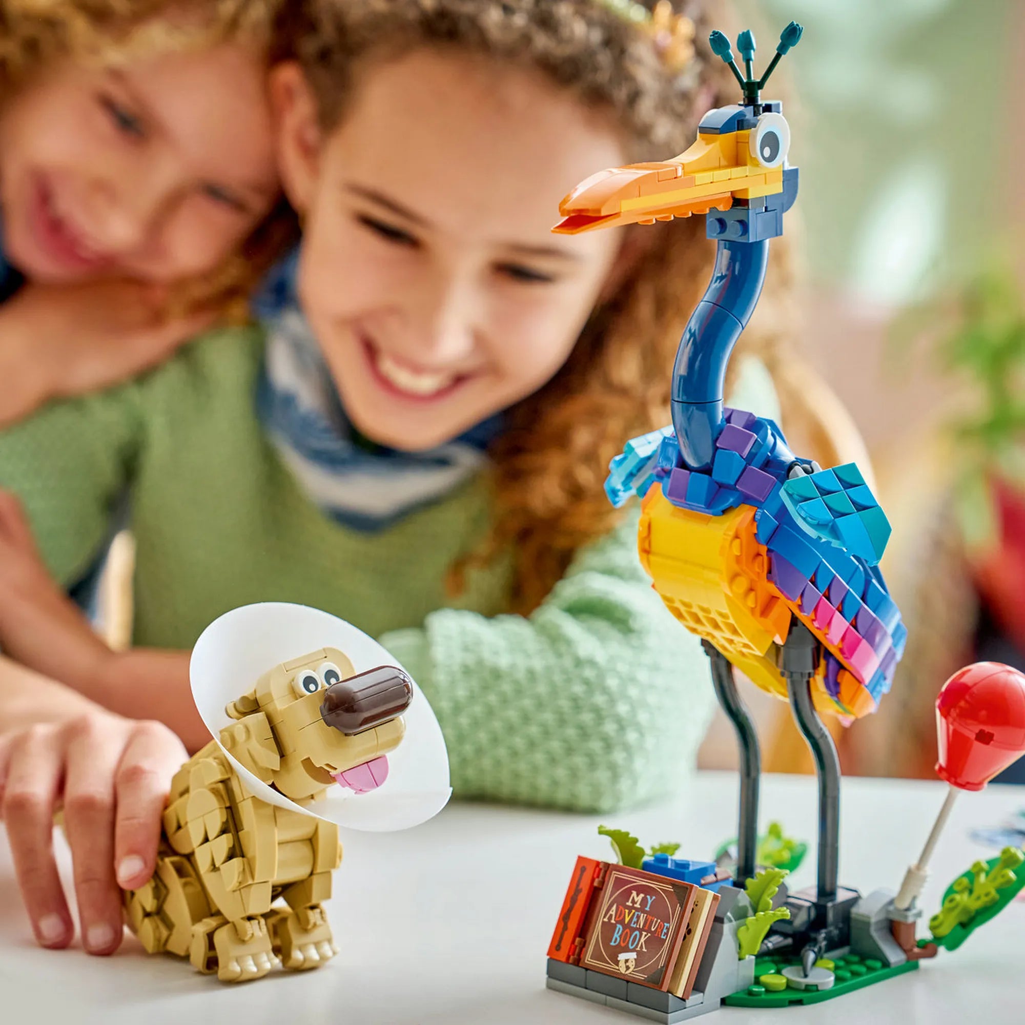 LEGO Disney: Kevin és Dug 43290, 628 darabos – gyerekek játszanak a Dug kutyát és Kevin madarat ábrázoló színes LEGO figurákkal az Up című filmből.