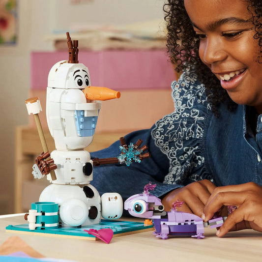 LEGO Disney: Olaf és Bruni vidám piknikezése 43287 – Gyerek játék közben Olaf és Bruni megépített figuráival az asztalon.
